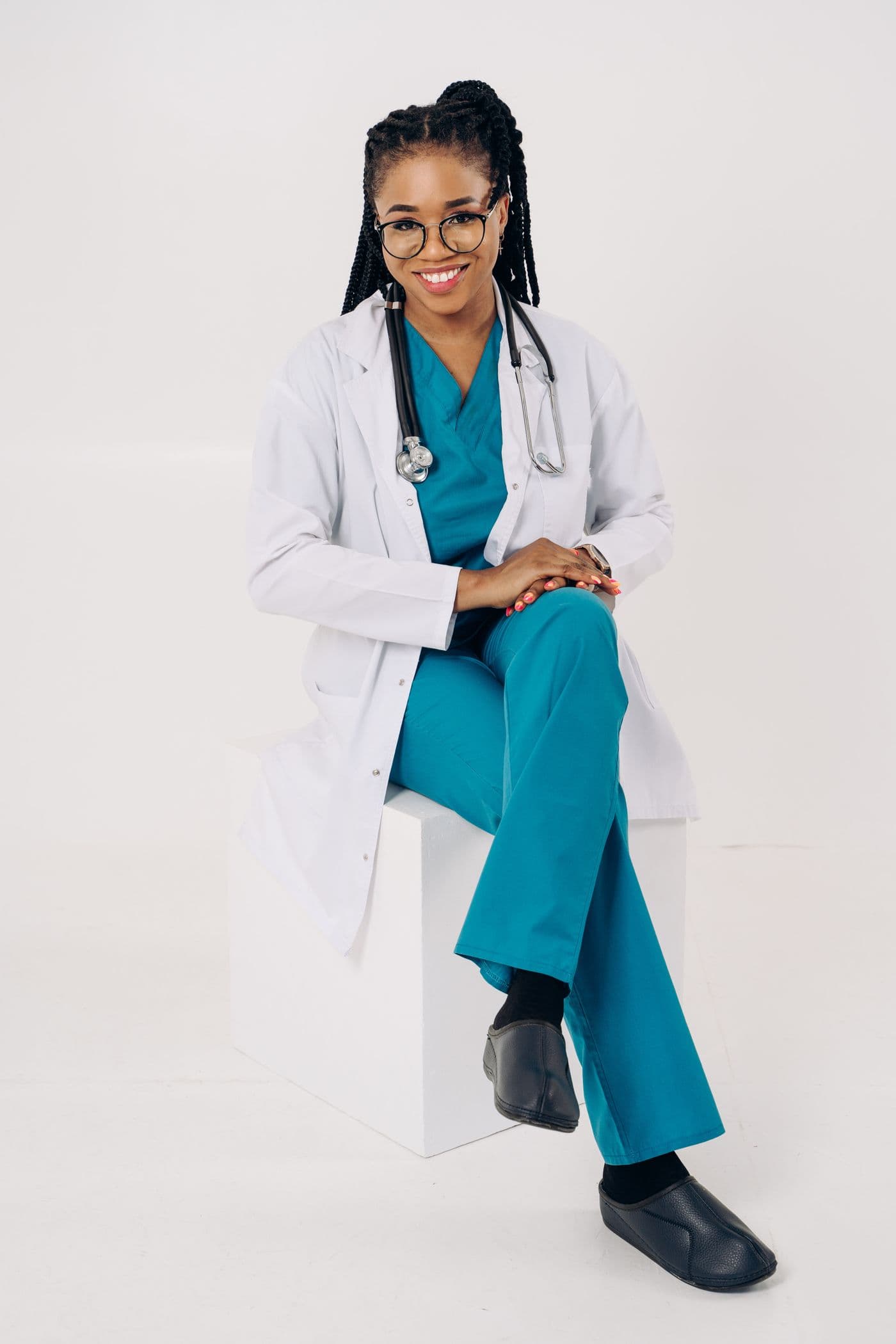 Danielle Okafor in scrubs and a lab coat, seated and smiling